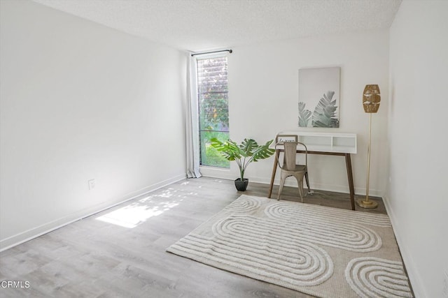 office space featuring wood finished floors, a textured ceiling, and baseboards