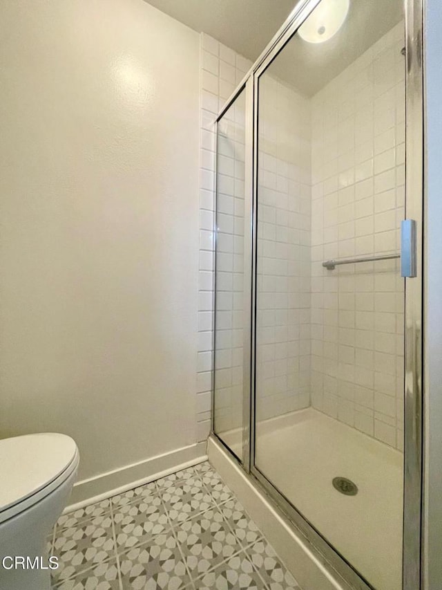 full bath featuring baseboards, a stall shower, tile patterned floors, and toilet