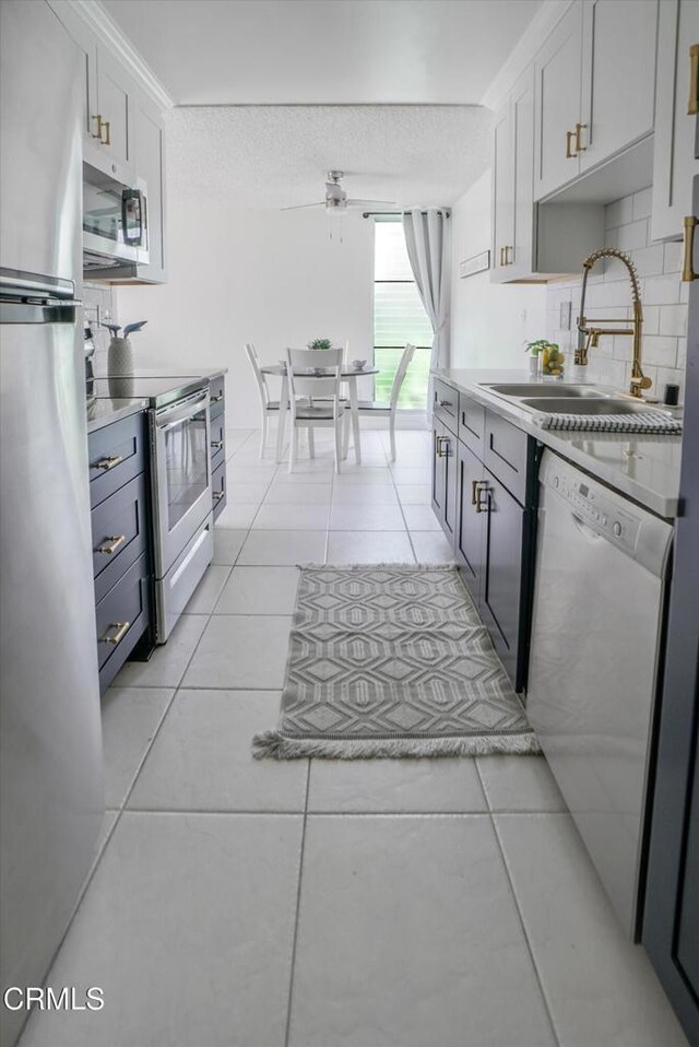 kitchen with stainless steel appliances, a sink, light tile patterned floors, tasteful backsplash, and light countertops