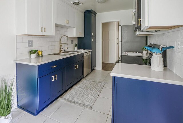 kitchen featuring stainless steel dishwasher, a sink, backsplash, blue cabinetry, and light countertops