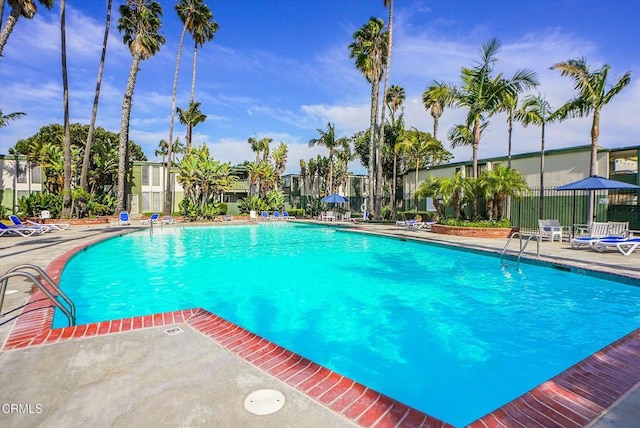 community pool with a patio area and fence