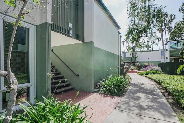 doorway to property featuring stucco siding and fence