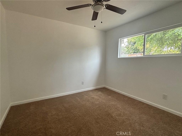 carpeted spare room featuring baseboards and a ceiling fan