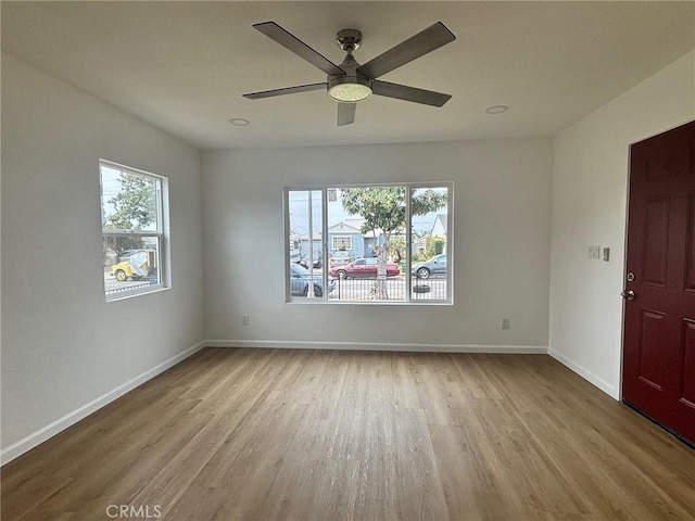 unfurnished room with wood finished floors, a ceiling fan, and baseboards