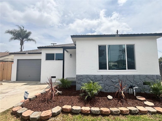 view of front of home with a garage, stucco siding, concrete driveway, and fence