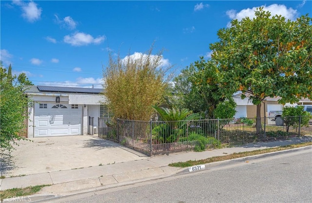 6371 Shawnee Rd, Westminster, CA 92683 - view of front of home featuring solar panels, concrete driveway, stucco siding, a fenced front yard, and a garage