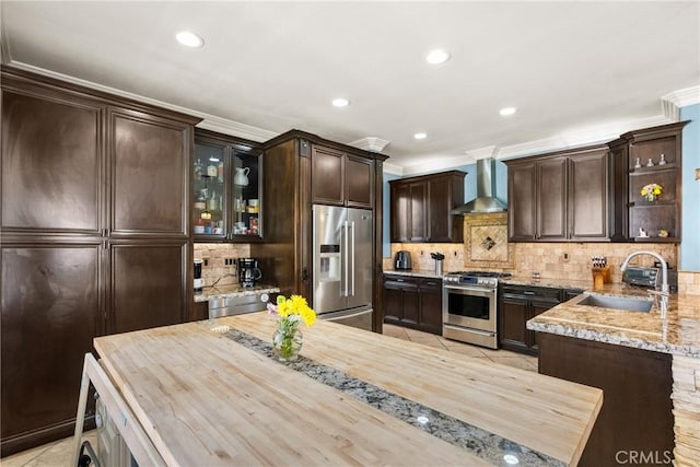 30463 Vineyard Ln, Castaic, CA 91384 - kitchen with stainless steel appliances, wall chimney exhaust hood, a sink, dark brown cabinets, and ornamental molding