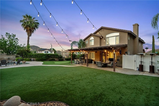 30463 Vineyard Ln, Castaic, CA 91384 - back of property at dusk with a patio area, stucco siding, and a chimney