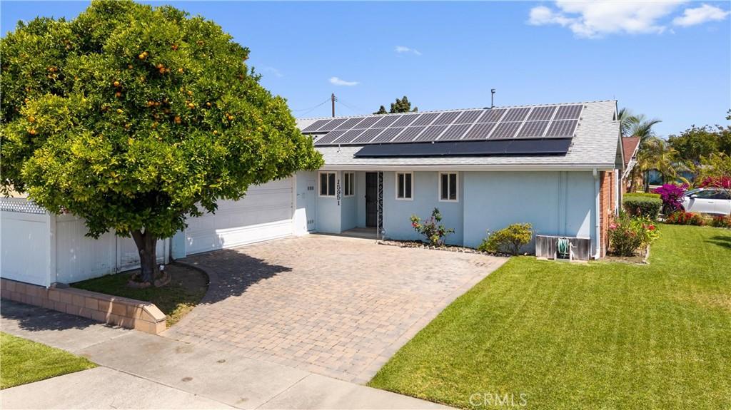 15951 Royal Pl, Westminster, CA 92683 - view of front facade featuring a front yard, an attached garage, decorative driveway, and solar panels