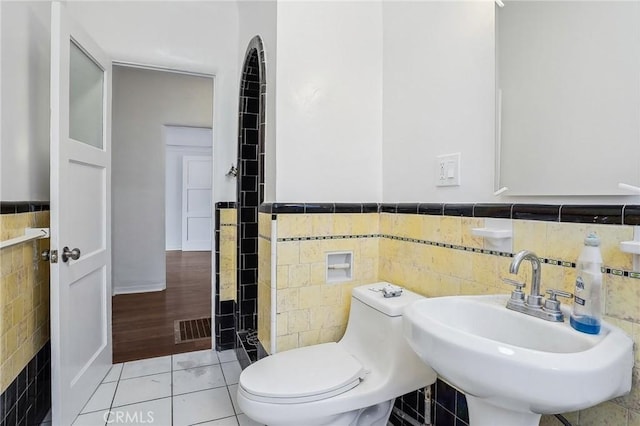 4235 Garthwaite Ave, Los Angeles, CA 90008 - bathroom featuring tile walls, a sink, toilet, wainscoting, and tile patterned floors