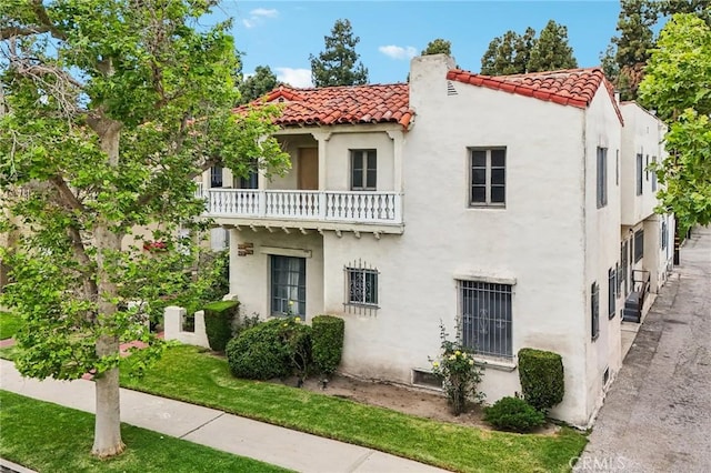 4235 Garthwaite Ave, Los Angeles, CA 90008 - mediterranean / spanish house featuring a tiled roof, stucco siding, a balcony, and a front lawn