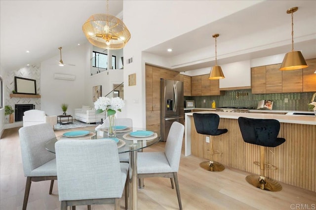 2464 Haller St, San Diego, CA 92104 - dining space with light wood-style floors, high vaulted ceiling, a premium fireplace, and ceiling fan