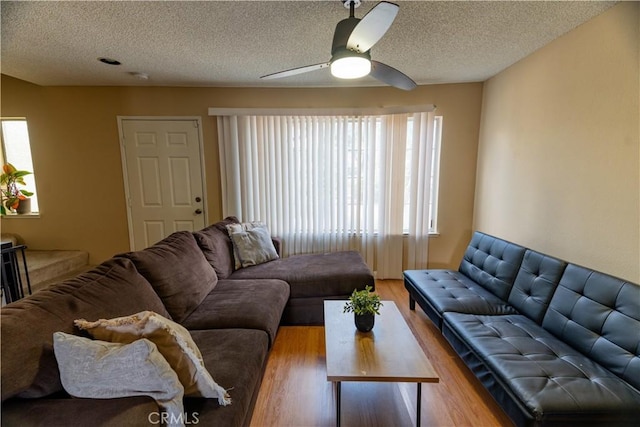 living area featuring wood finished floors, ceiling fan, and a textured ceiling