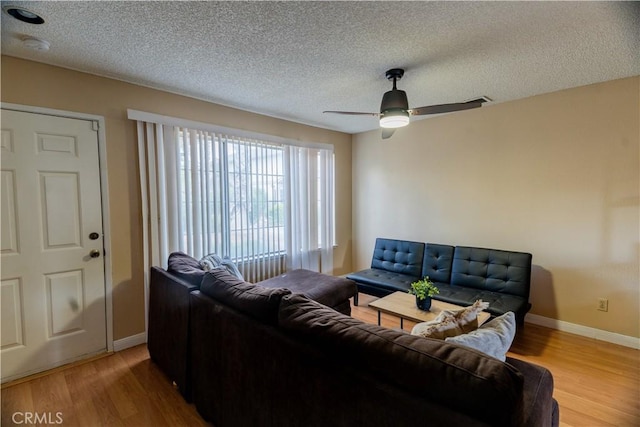 living area featuring wood finished floors, a textured ceiling, baseboards, and a ceiling fan