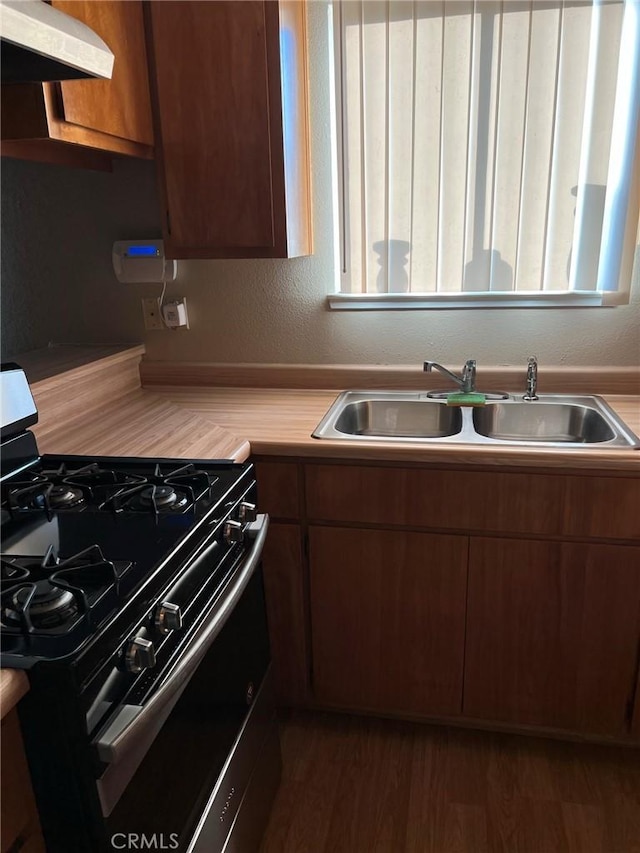kitchen with range with gas cooktop, exhaust hood, light countertops, a sink, and plenty of natural light