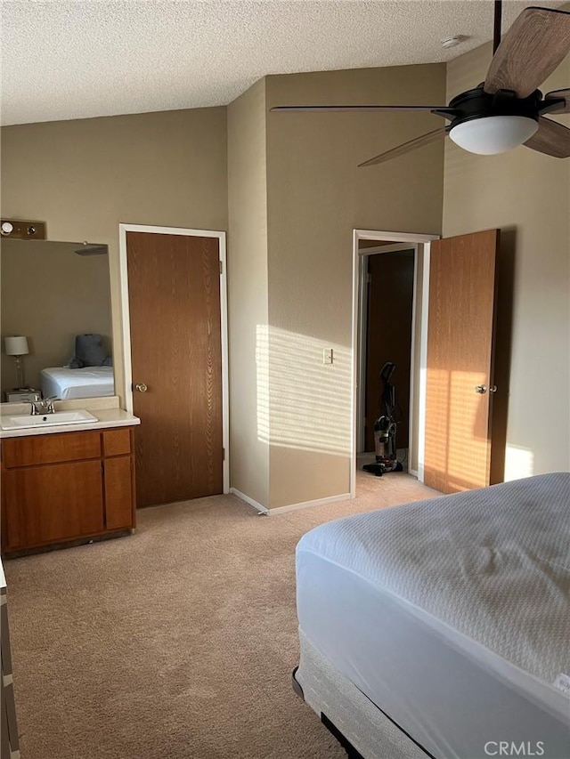 bedroom with a sink, light carpet, ceiling fan, and a textured ceiling