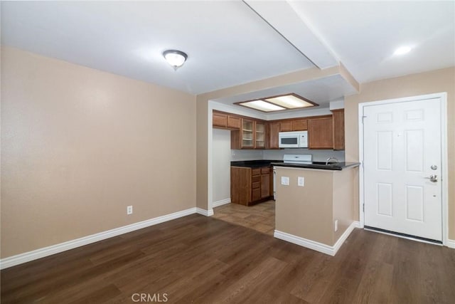 200 E Alessandro Blvd Unit 97, Riverside, CA 92508 - kitchen featuring white microwave, dark countertops, brown cabinetry, dark wood finished floors, and a peninsula