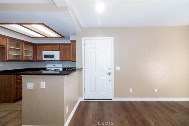 200 E Alessandro Blvd Unit 97, Riverside, CA 92508 - kitchen with white appliances, brown cabinetry, dark countertops, wood finished floors, and glass insert cabinets