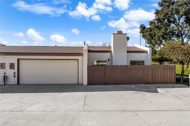 view of front of property with fence, stucco siding, concrete driveway, and an attached garage
