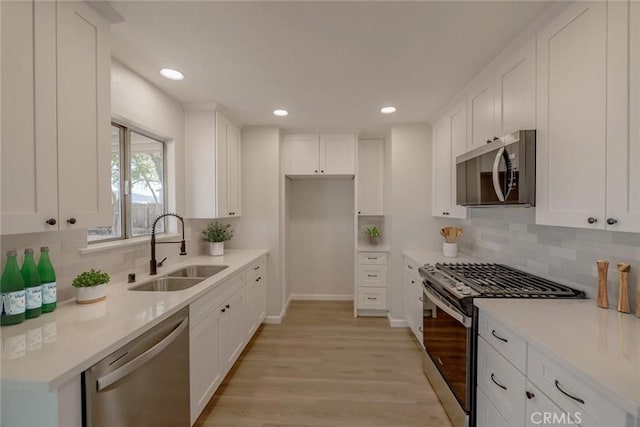 21918 Mohican Ave, Apple Valley, CA 92307 - kitchen featuring stainless steel appliances, light wood finished floors, backsplash, white cabinets, and recessed lighting