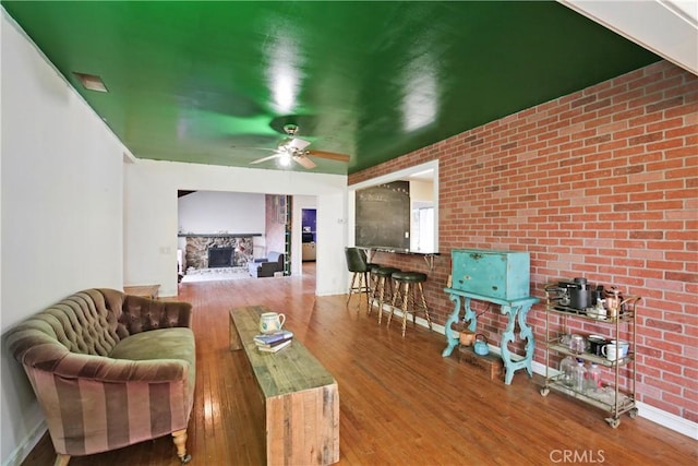 5408 Whitewood Ave, Lakewood, CA 90712 - living area with a wood stove, wood finished floors, a fireplace, ceiling fan, and brick wall