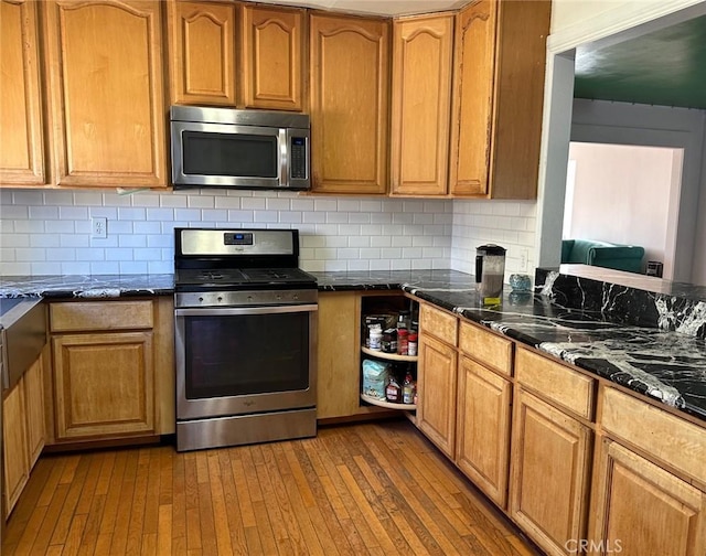 5408 Whitewood Ave, Lakewood, CA 90712 - kitchen with stainless steel appliances, wood-type flooring, tasteful backsplash, dark stone countertops, and brown cabinets