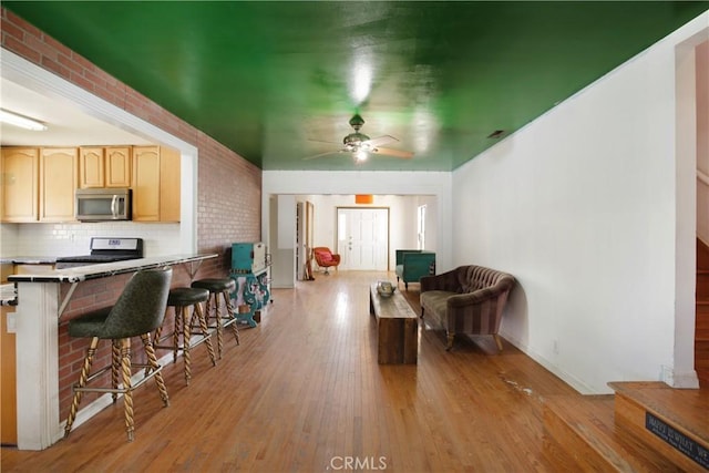 5408 Whitewood Ave, Lakewood, CA 90712 - kitchen with stainless steel appliances, a breakfast bar area, light brown cabinets, light wood-style floors, and open floor plan