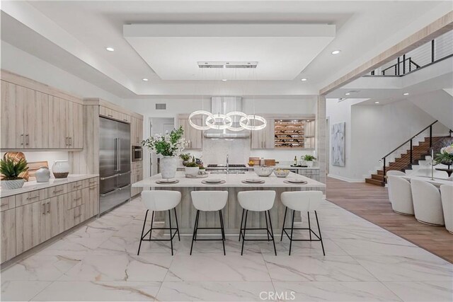 59 Dorado, Irvine, CA 92618 - kitchen with range hood, stainless steel built in fridge, a raised ceiling, a kitchen bar, and light marble finish flooring