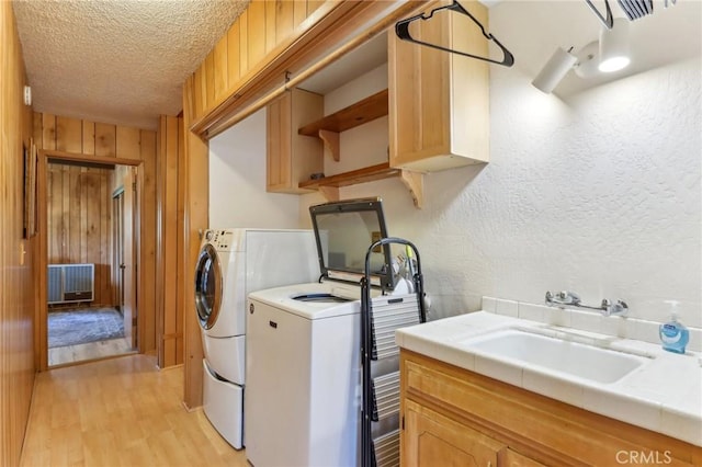 24514 Albrun Dr, Crestline, CA 92325 - laundry room featuring a textured ceiling, independent washer and dryer, cabinet space, light wood-type flooring, and wood walls