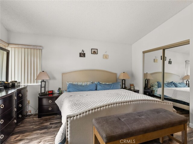 bedroom featuring dark wood finished floors, a closet, a textured ceiling, and vaulted ceiling