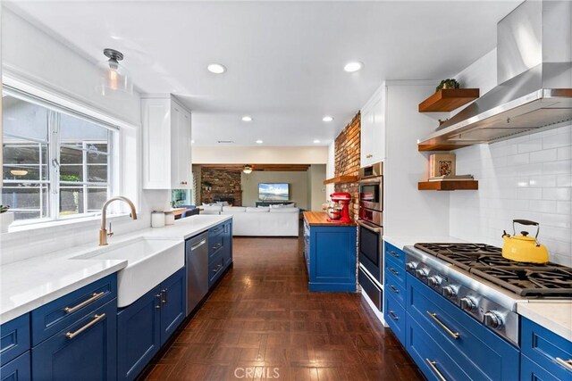 2618 N Louise St, Santa Ana, CA 92706 - kitchen with blue cabinetry, wall chimney range hood, open shelves, a sink, and recessed lighting