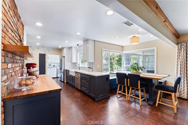 2618 N Louise St, Santa Ana, CA 92706 - kitchen featuring wood counters, stainless steel appliances, a sink, washer / dryer, and a kitchen bar