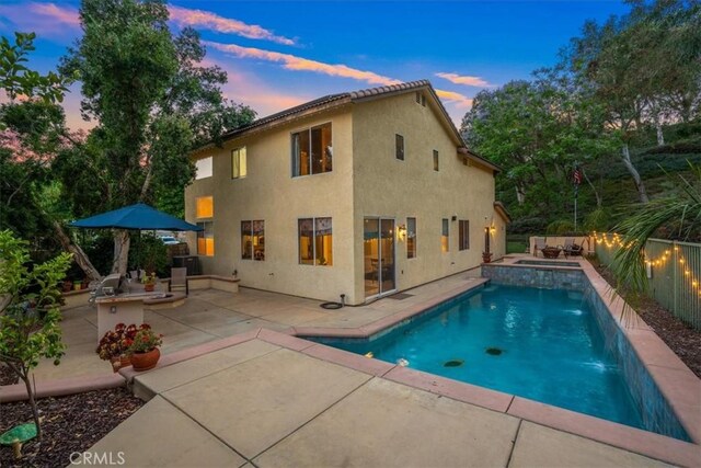 28335 Arroyo Ct, Castaic, CA 91384 - back of property at dusk featuring a fenced backyard, stucco siding, a patio area, and a pool with connected hot tub