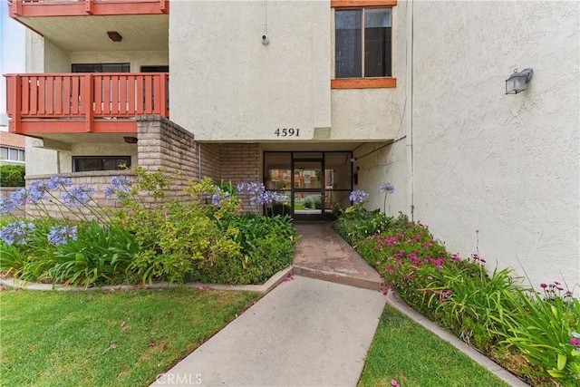 4591 Orange Ave Unit 306, Long Beach, CA 90807 - view of exterior entry with stucco siding, a balcony, and brick siding