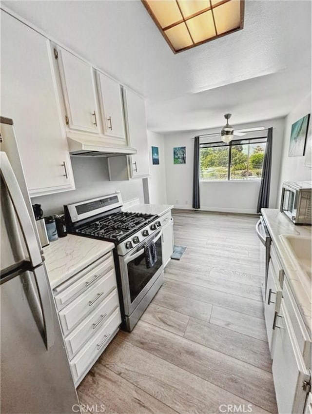 4591 Orange Ave Unit 306, Long Beach, CA 90807 - kitchen featuring under cabinet range hood, stainless steel appliances, light wood-style flooring, and white cabinetry