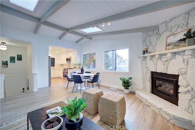 953 Sheffield St, Cambria, CA 93428 - living room featuring a skylight, a stone fireplace, light wood-style floors, and baseboards