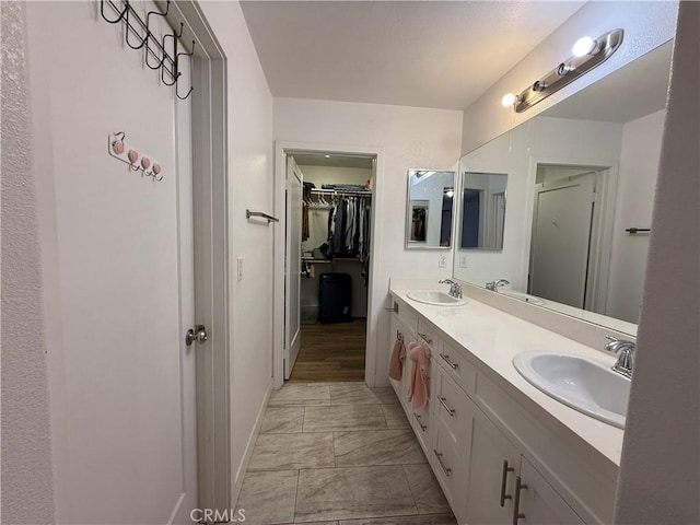 full bath with marble finish floors, baseboards, double vanity, and a walk in closet