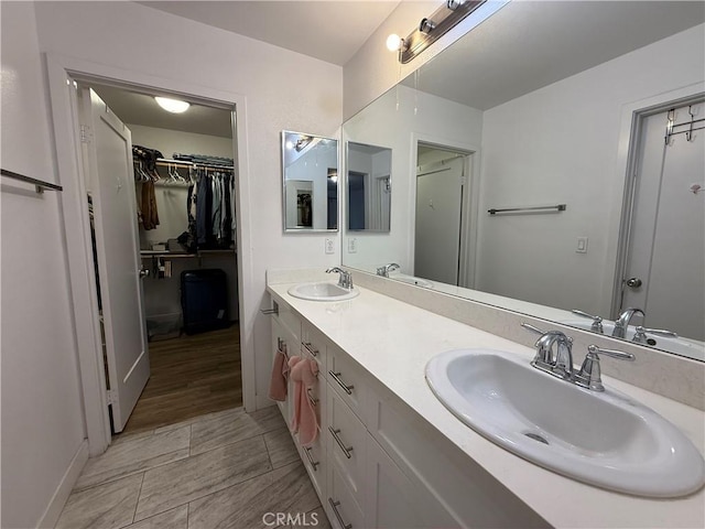 bathroom featuring double vanity, a spacious closet, and baseboards