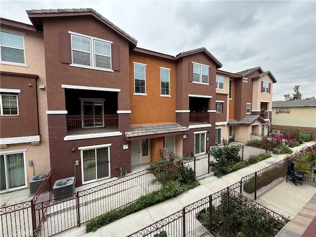 view of building exterior featuring central AC unit and a fenced front yard
