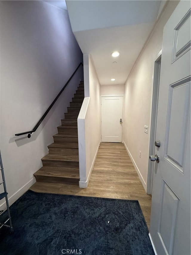 staircase with baseboards, wood finished floors, and recessed lighting