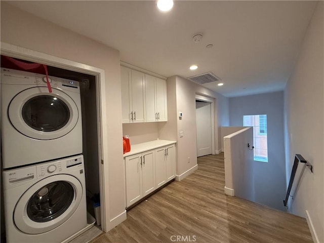washroom featuring stacked washing machine and dryer, wood finished floors, baseboards, and recessed lighting