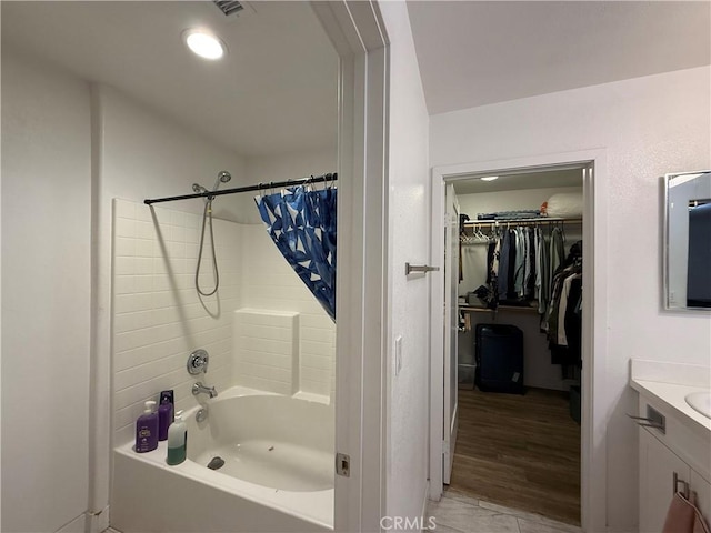 bathroom with vanity, a spacious closet, shower / bath combination with curtain, and wood finished floors