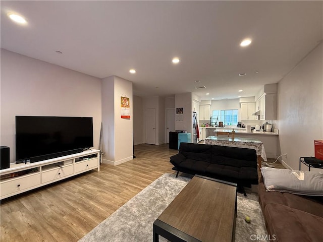 living area with light wood-style floors, baseboards, and recessed lighting