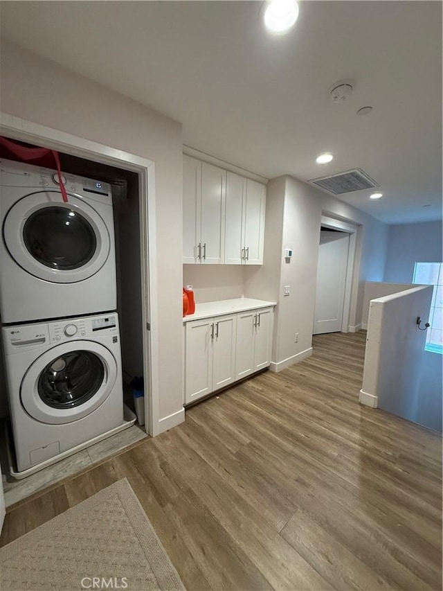 laundry area with stacked washing machine and dryer, light wood-style flooring, baseboards, and recessed lighting