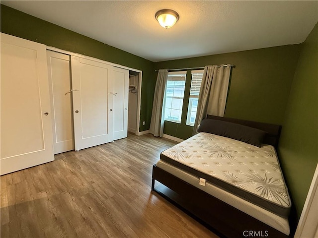 bedroom featuring wood finished floors, baseboards, and a closet