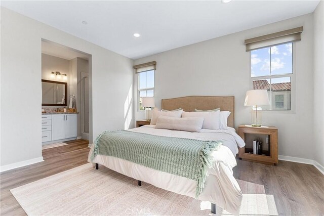 bedroom with wood finished floors, baseboards, recessed lighting, and ensuite bathroom