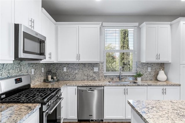kitchen featuring appliances with stainless steel finishes, a sink, white cabinets, and backsplash