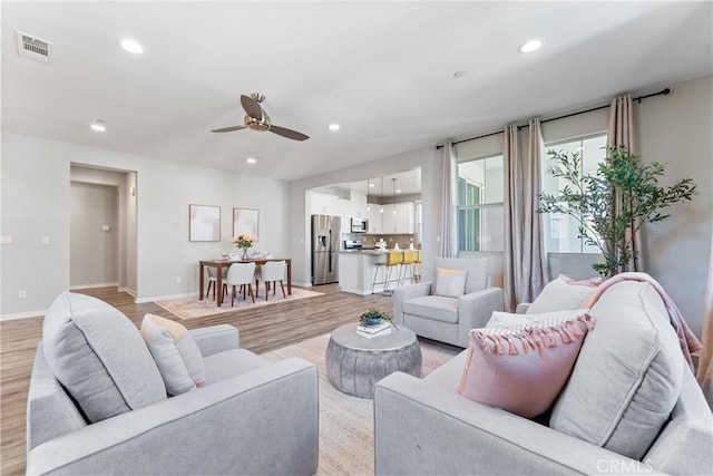 living room featuring a ceiling fan, recessed lighting, light wood-style floors, and baseboards