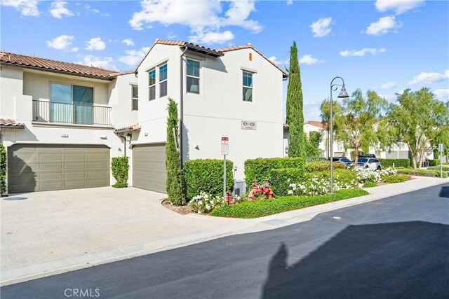 view of front of home featuring a garage, a tile roof, stucco siding, and concrete driveway