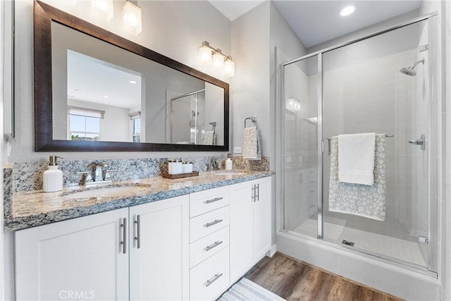 full bathroom featuring a shower stall, wood finished floors, and double vanity